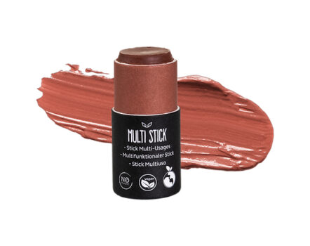 Een multifunctionele cosmetische stick naast zijn kleurstaal, met een romige, gedempte roodbruine tint met hints van zachtroze.