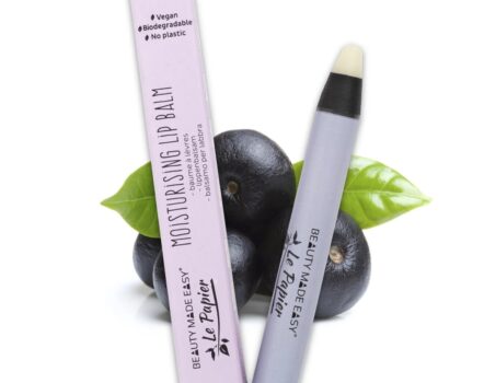 Afbeelding van Beauty Made Easy's Acai Moisturizing Lip Balm in biologisch afbreekbare verpakking, met de nadruk op veganistische en plasticvrije eigenschappen, met acaibessen en een groen blad op de achtergrond