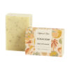 cream colored solid soap scrub next to peach and cream colored paper packaging