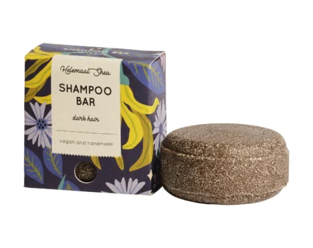 dark circular shampoo bar for dark hair next to a purple and dark blue cardboard packaging