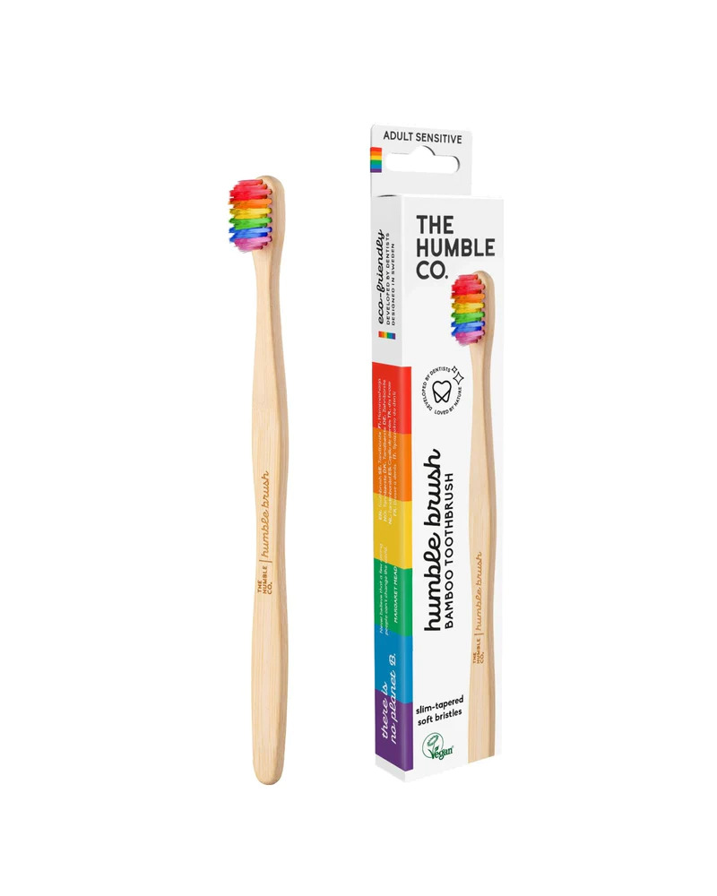 Bamboo toothbrush with rainbow bristles next cardboard packaging with rainbow details and an image of the bamboo toothbrush