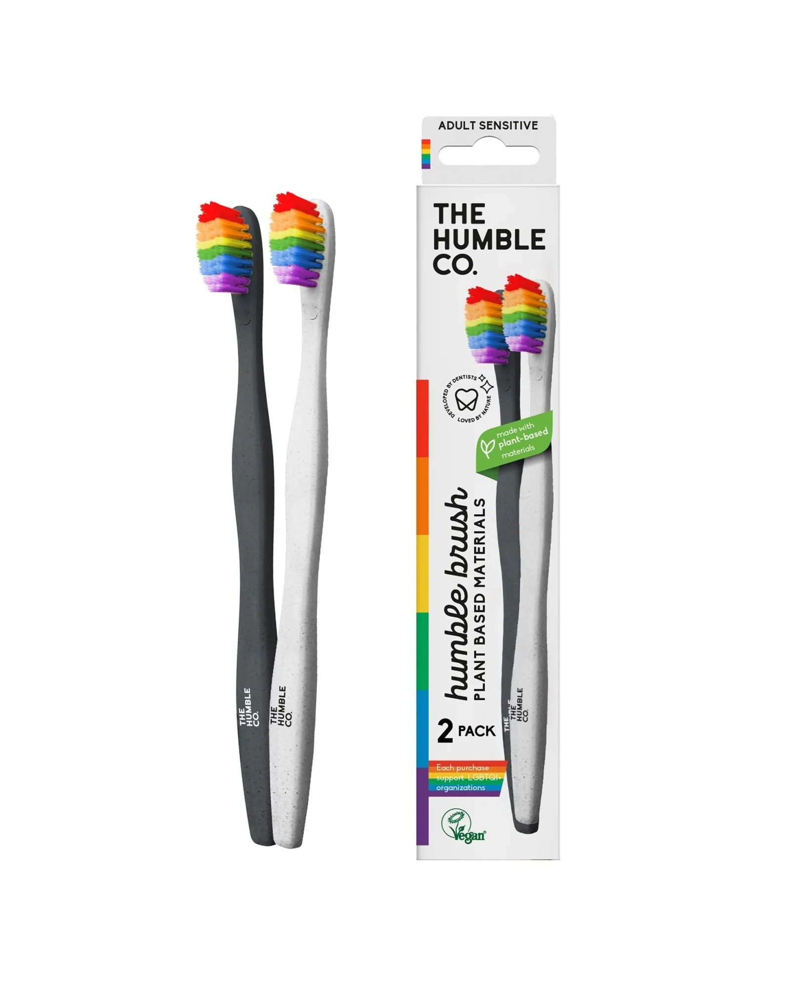 two vegan toothbrushes, one with a grey handle, one with a white handle, both with rainbow nylon bristles next to a white box with a picture of both toothbrushes on it