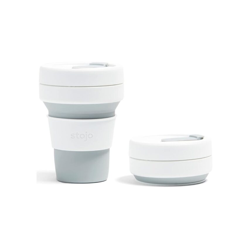 A fully expanded Stojo collapsible cup in a light gray and white color, placed next to its collapsed version to showcase its compact design.